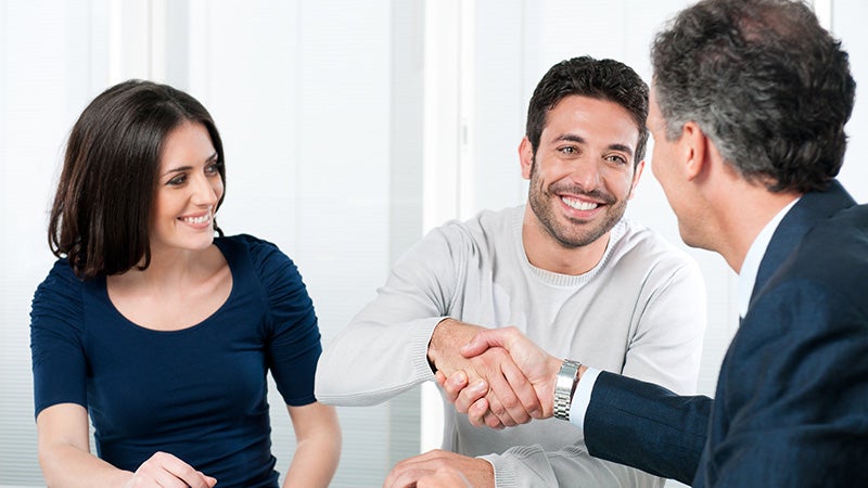 Couple smiling and handshaking with Sales person